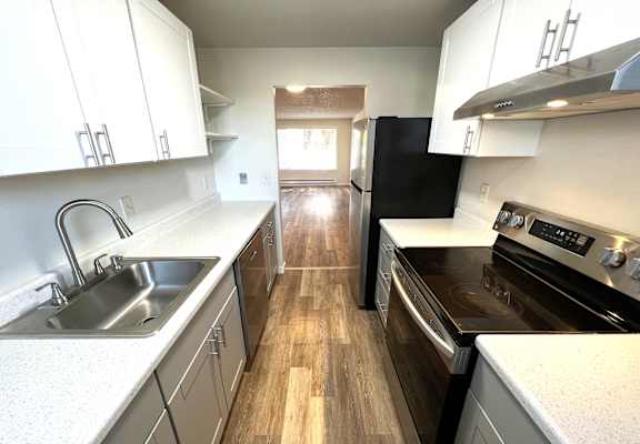 A kitchen with white cabinets and a black refrigerator.