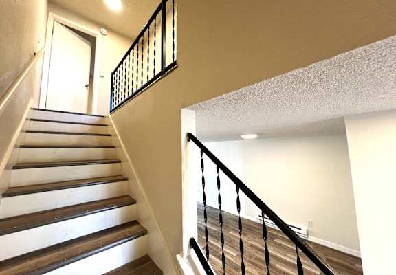A staircase with a black railing and wooden steps.