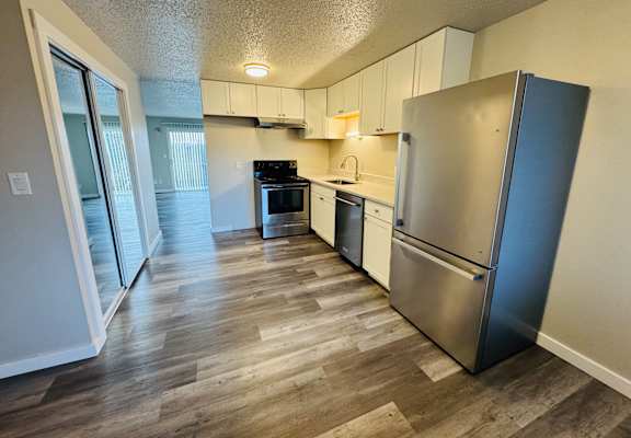 A kitchen with a refrigerator, stove, and sink.