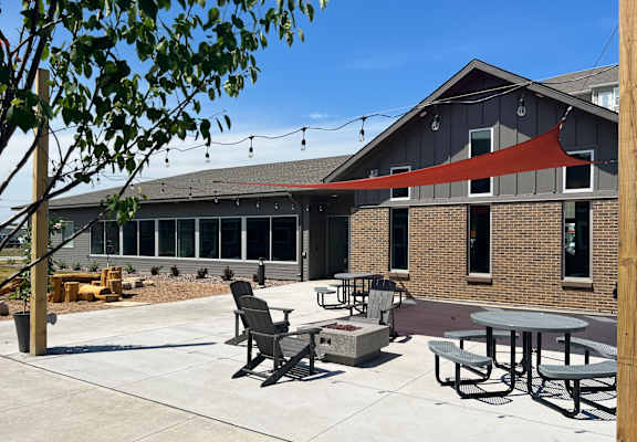 a patio with tables and chairs and a firepit in front of a building