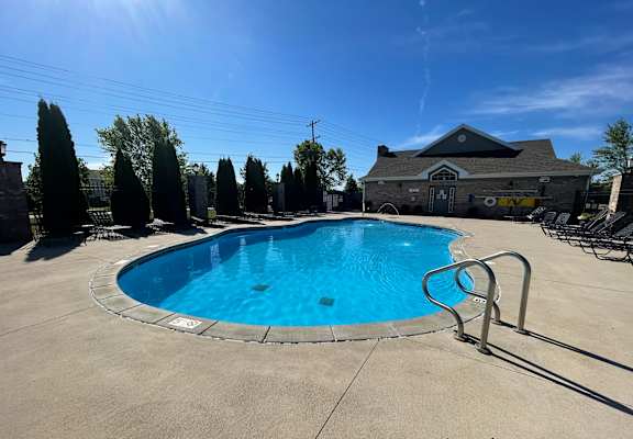 a resort style pool with chairs around it and a house in the background