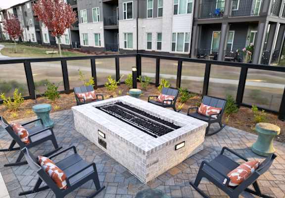 A patio with a fire pit and chairs.