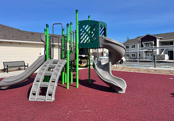 A playground with a green slide and a grey slide.