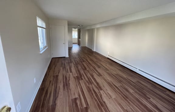 an empty living room with hardwood floors and large windows