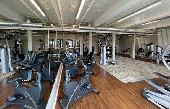 a gym with cardio machines and weights on a wooden floor