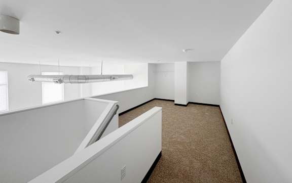 A white room with a carpeted floor and a skylight.