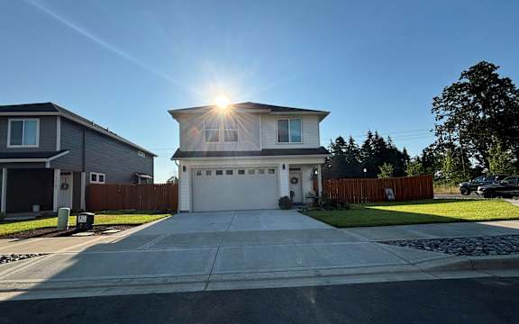a white house with the sun shining over the driveway
