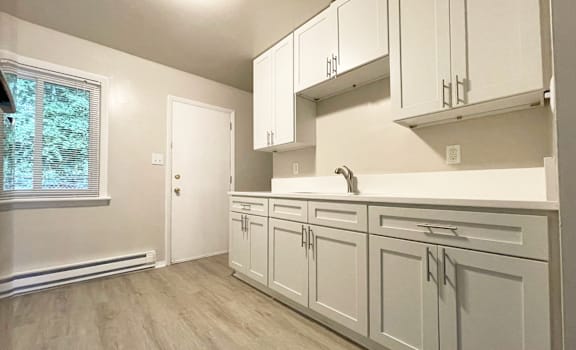 A kitchen with white cabinets and a window.