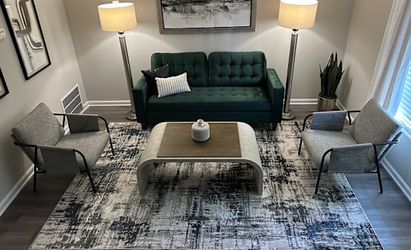 A living room with a green couch, two chairs, a coffee table, and two floor lamps.