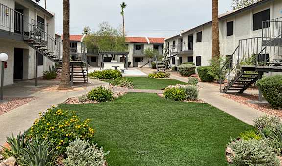 A courtyard with a lawn and a building in the background.