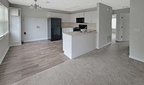 A kitchen area with a black fridge and microwave.
