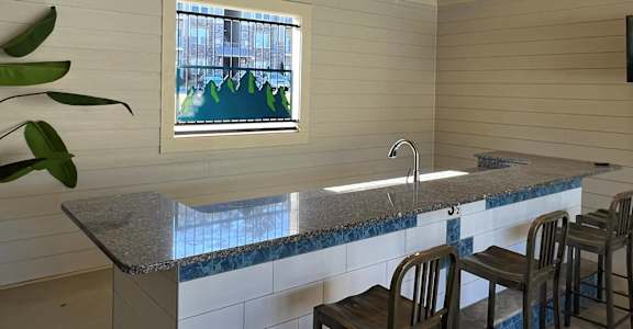 a kitchen with a counter and chairs and a sink