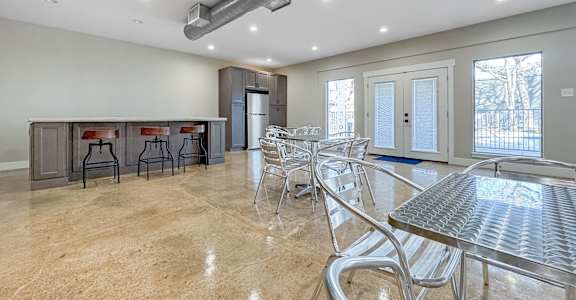A spacious dining area with a bar and chairs.
