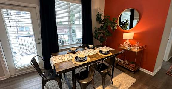 a dining room with an orange wall and a table with plates and chairs