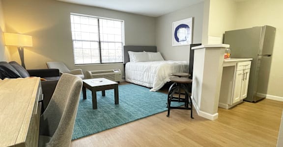 A bedroom with a bed, chair, and a small table.