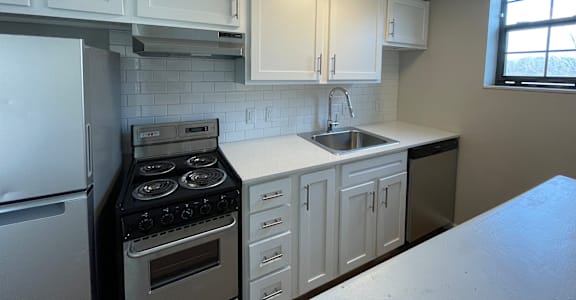 A kitchen with white cabinets and a stove top oven.