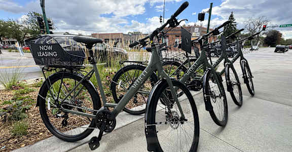 A bicycle leasing station with bikes parked in it.