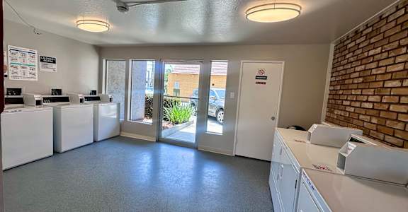 an empty kitchen with white appliances and a brick wall