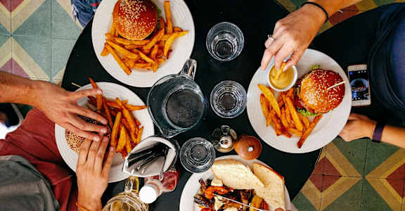 A top view of a group of people sharing a meal with burgers and fries.