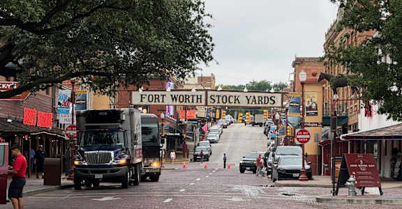A street view of Fort Worth Stock Yards with trucks and people.