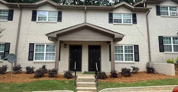 A two-story house with a black front door and windows with black shutters at Waverly Manor Townhomes, Norcross, GA 30071