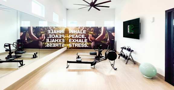 A gym room with exercise equipment and a wall mural promoting inhalation, exhalation, peace, and stress relief.