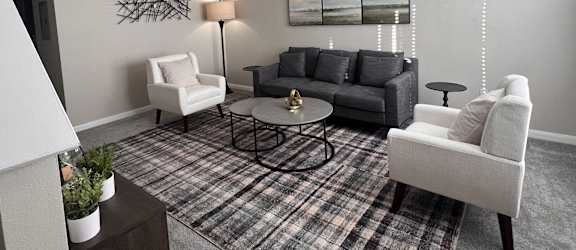 a living room with couches and chairs and a rug