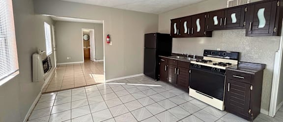 A kitchen with white tiled floors and dark brown cabinets.