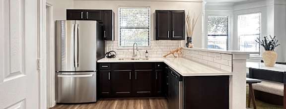 a kitchen with black cabinets and a stainless steel refrigerator at Grand Villas Apartments, Katy
