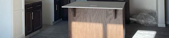 A white cabinet with drawers and shelves is in a room with light coming through a window.