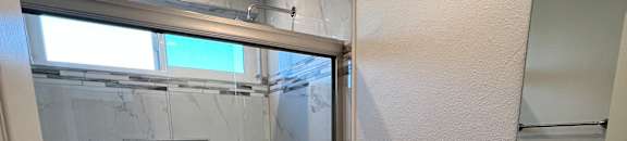 View of bathroom with walk in tile shower, well lit window above, toilet, and sink