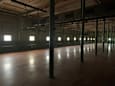 A large empty room with wooden floors and a series of windows on the wall.