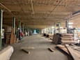 A construction site with a large open space and wooden beams on the floor.
