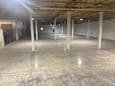 A large, empty basement with concrete floors and white pillars.