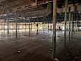 A large, empty warehouse with wooden floors and green pillars.
