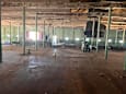 A large, empty warehouse with a concrete floor and green pillars.