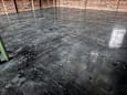 A black polished concrete floor with a green pole on the left side.