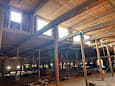 A large unfinished room with wooden beams and windows.