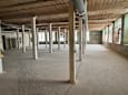 A large, empty warehouse with concrete floors and exposed ceiling beams.