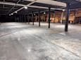 A large, empty warehouse with concrete floors and yellow lines.