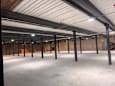 A large, empty warehouse with a white ceiling and concrete floor.