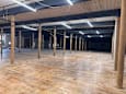 A large empty warehouse with wooden floors and pillars.