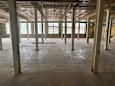 A large, empty warehouse with concrete floors and metal beams.