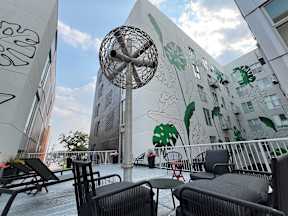 A patio with chairs and a table is in front of a building with graffiti on it.