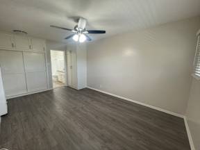 an empty living room with wood floors and a ceiling fan