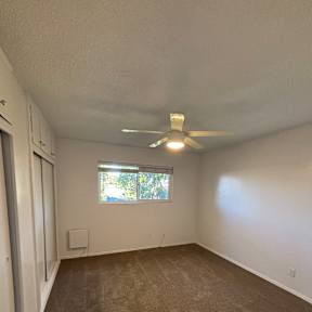 A room with a ceiling fan and a window.