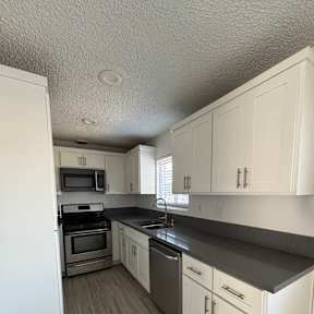 A kitchen with white cabinets and a white refrigerator.