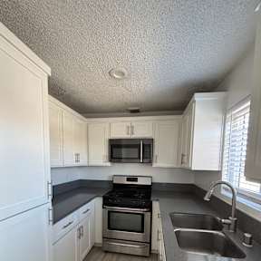 A kitchen with white cabinets and a microwave.