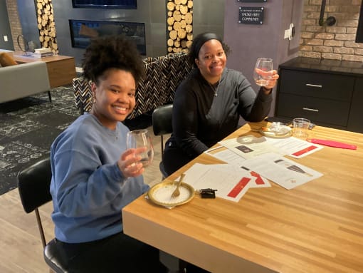 two women sitting at a table holding up glasses of wine