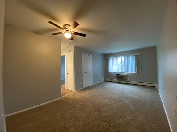 an empty living room with a ceiling fan